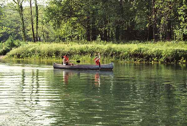 photo of two campers having fun and relaxing by exploring in a canoe while camping