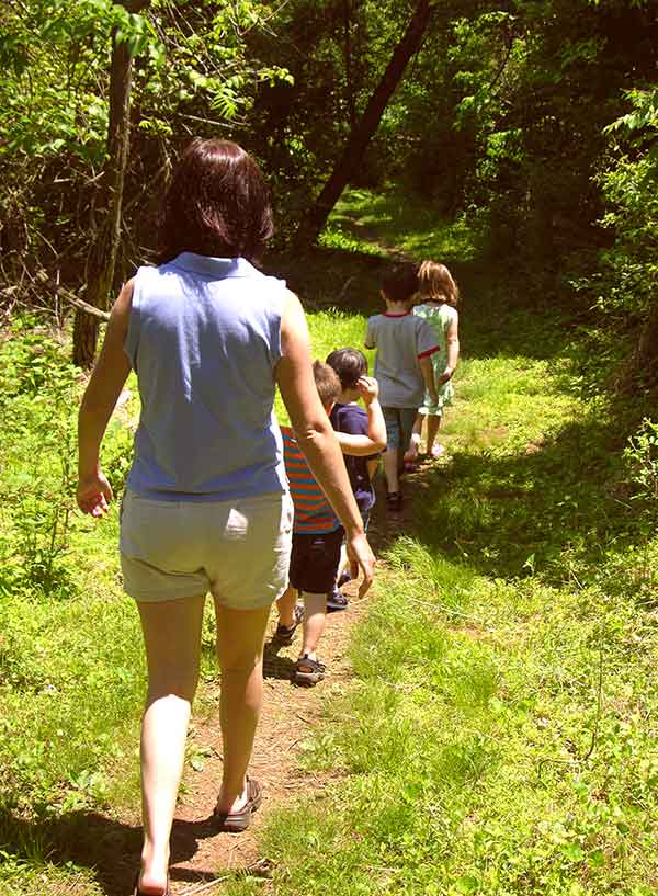 photo of mom and kids hiking along a trail is a great example of ways to camp and have fun with your family