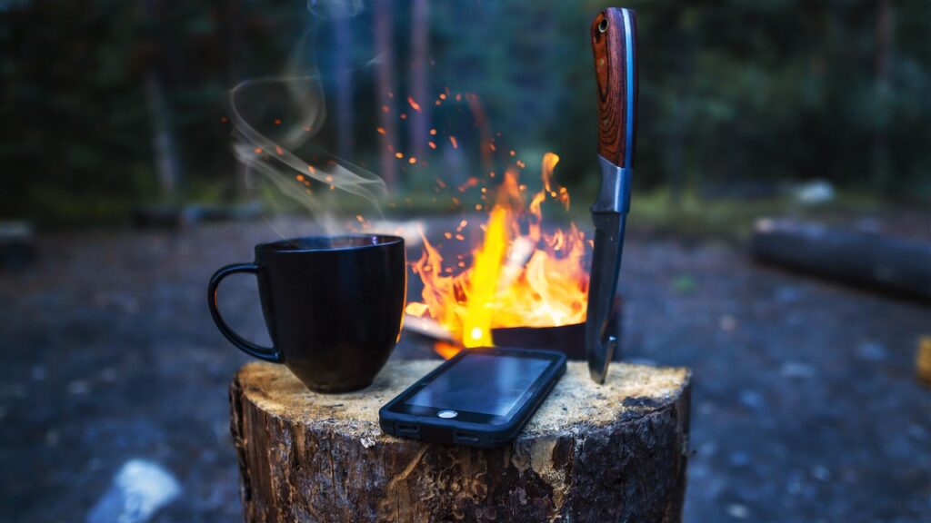 photo of a smartphone on a block of wood in a campsite