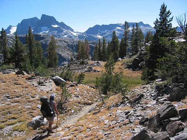 photo of a woman hiking a trail in the mountains from have an incredible camping experience with these good ideas