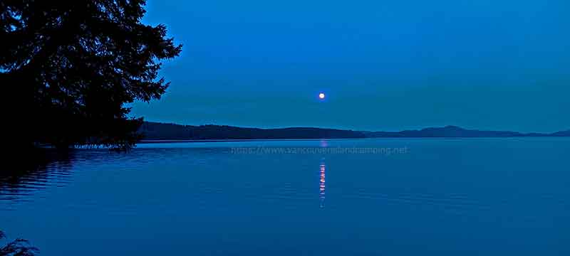 photo of a full moon at twilight over lower campbell lake on Vancouver Island British Columbia Canada