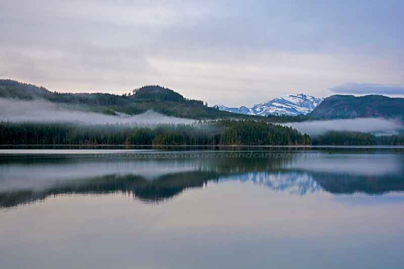 photo of a fog bank with a snow covered mountain in the background from Loon Bay Campsite on Vancouver Island British Columbia, Canada