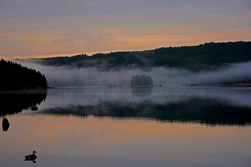 photo of a foggy morning sunrise over Campbell Lake at Loon Bay Campground on Vancouver Island British Columbia, Canada
